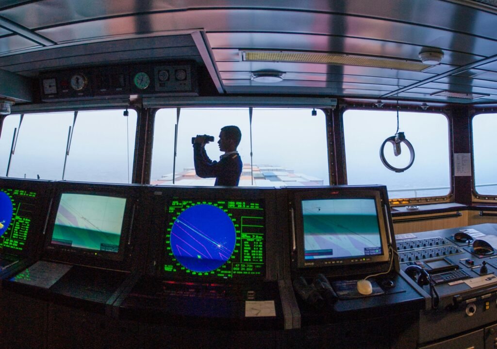 Silhouette of a navigator using binoculars on a cargo ship